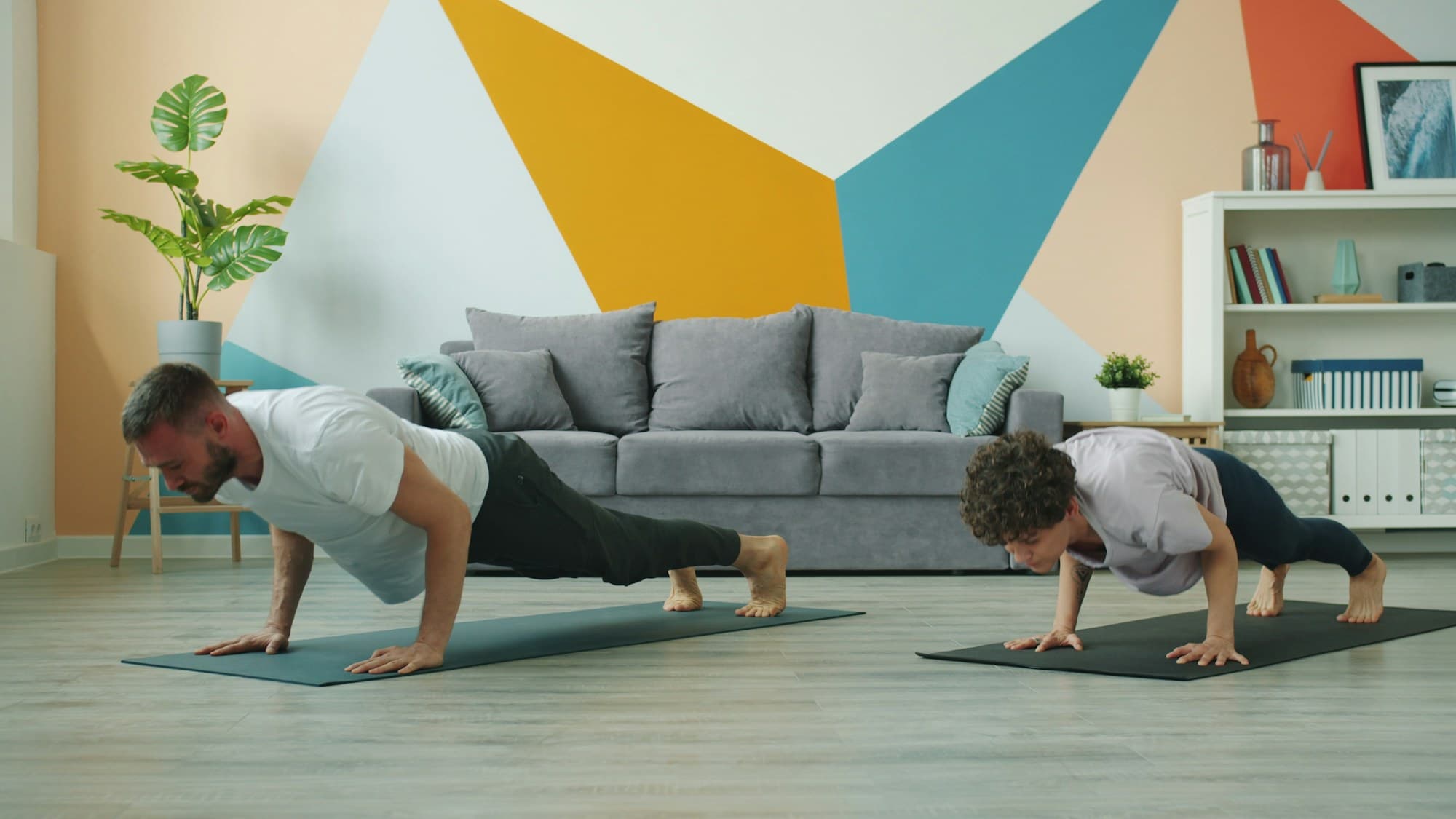 Man and woman doing push-ups on yoga mats.